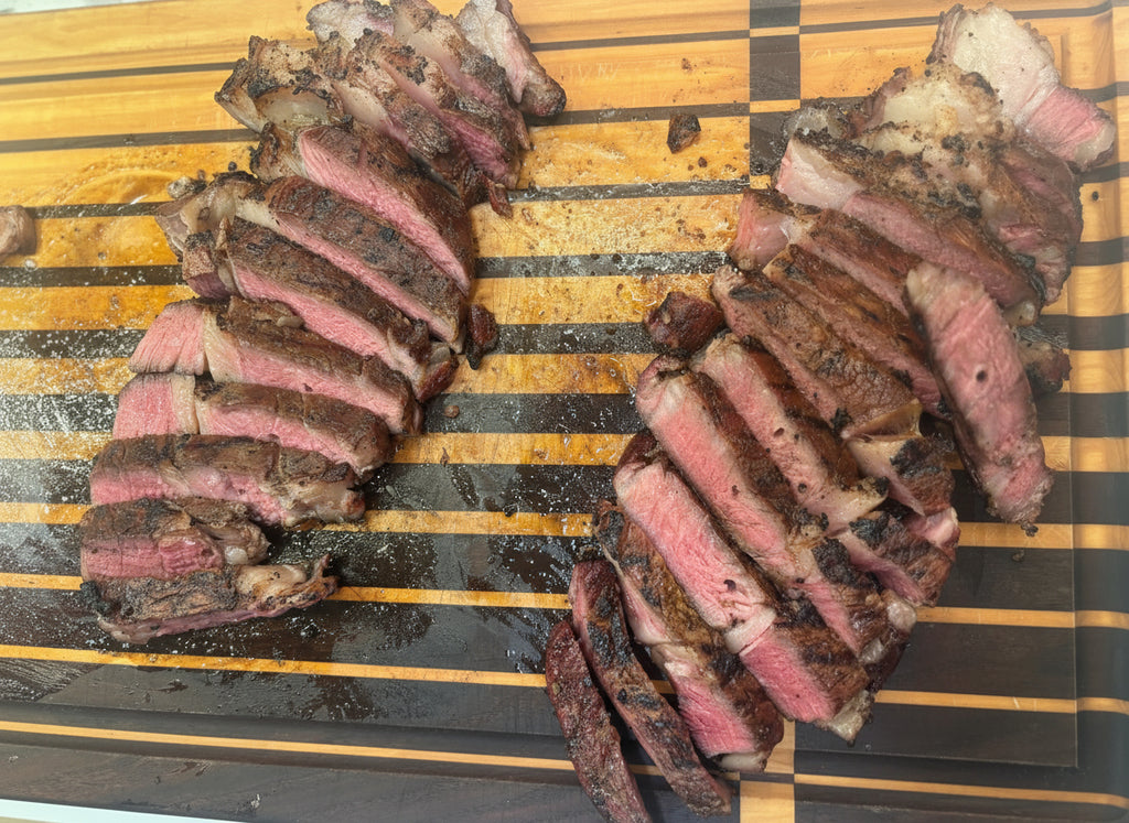 Sliced Nebraska raised ribeye steak on a striped wooden cutting board