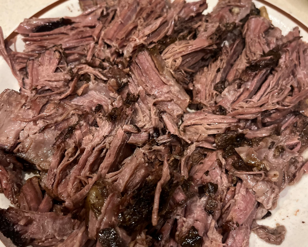 Shredded beef on a white plate with a brown rim