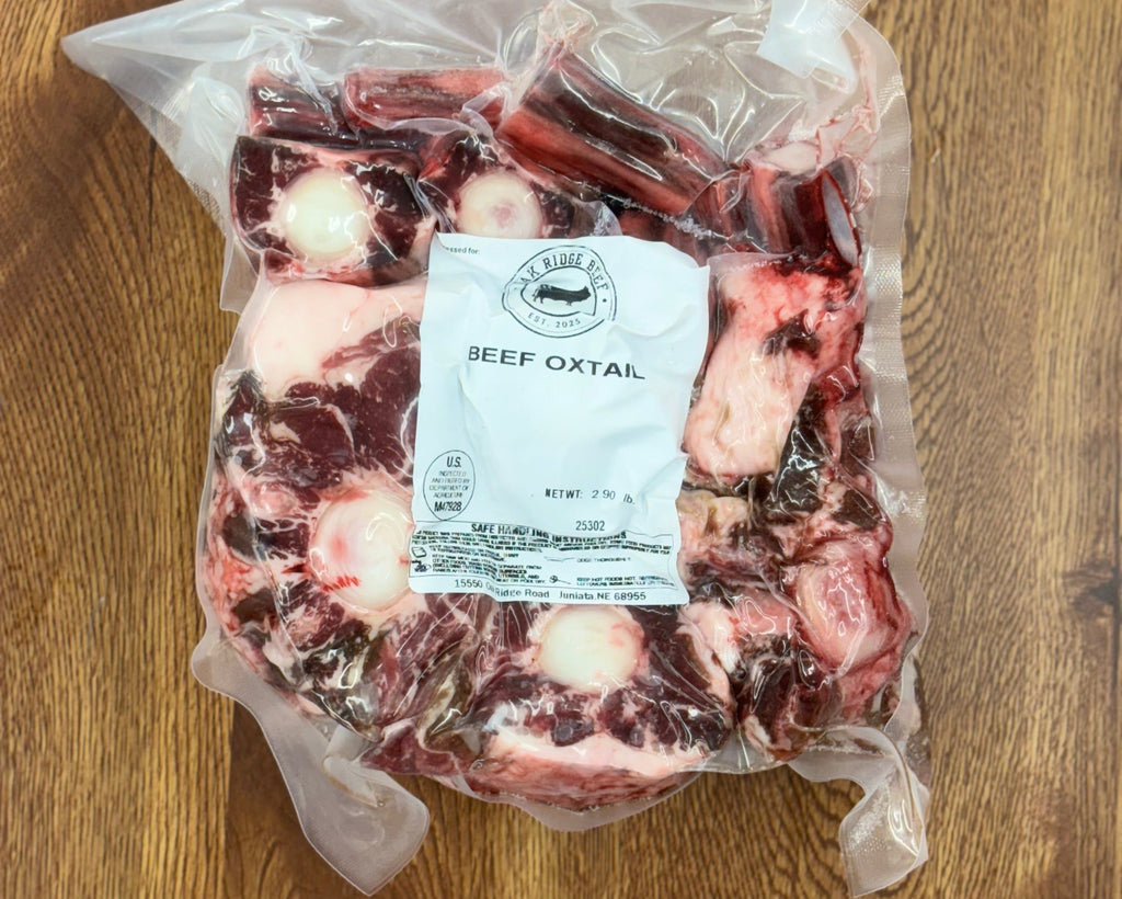 Packaged beef oxtail on a wooden surface with a label.