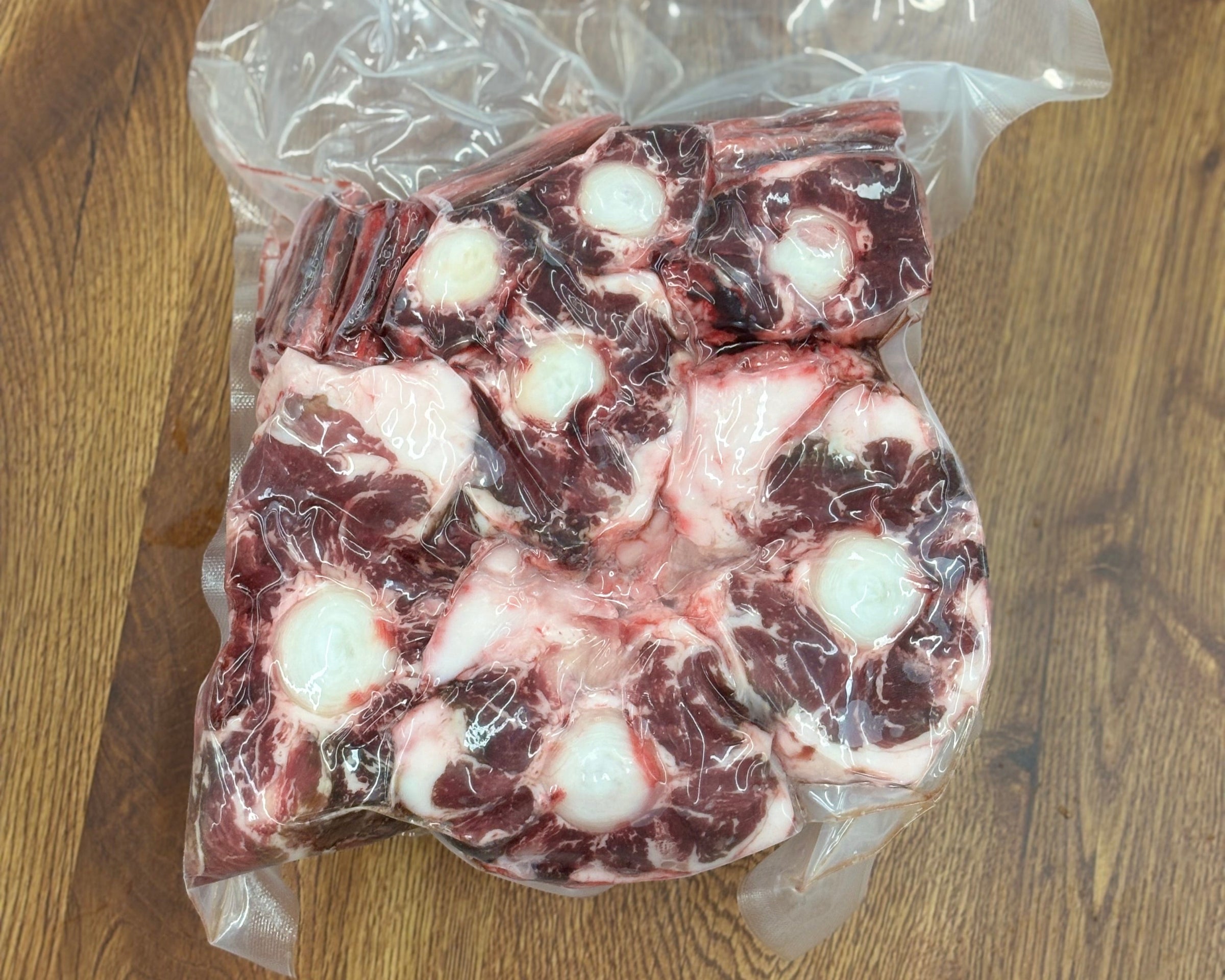 Vacuum-sealed package of raw beef on a wooden surface