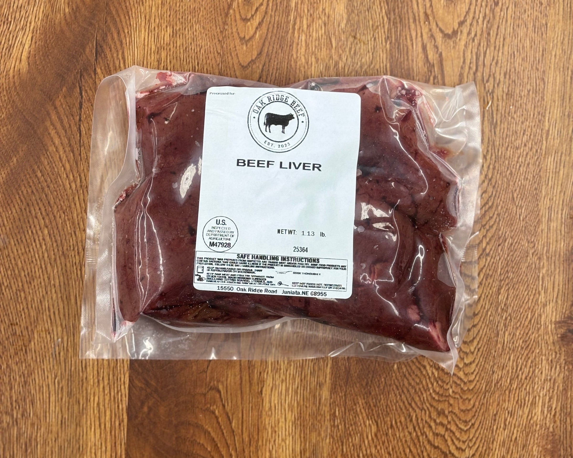 Packaged beef liver on a wooden surface with a label.