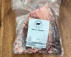 Packaged beef heart on a wooden surface with a label.
