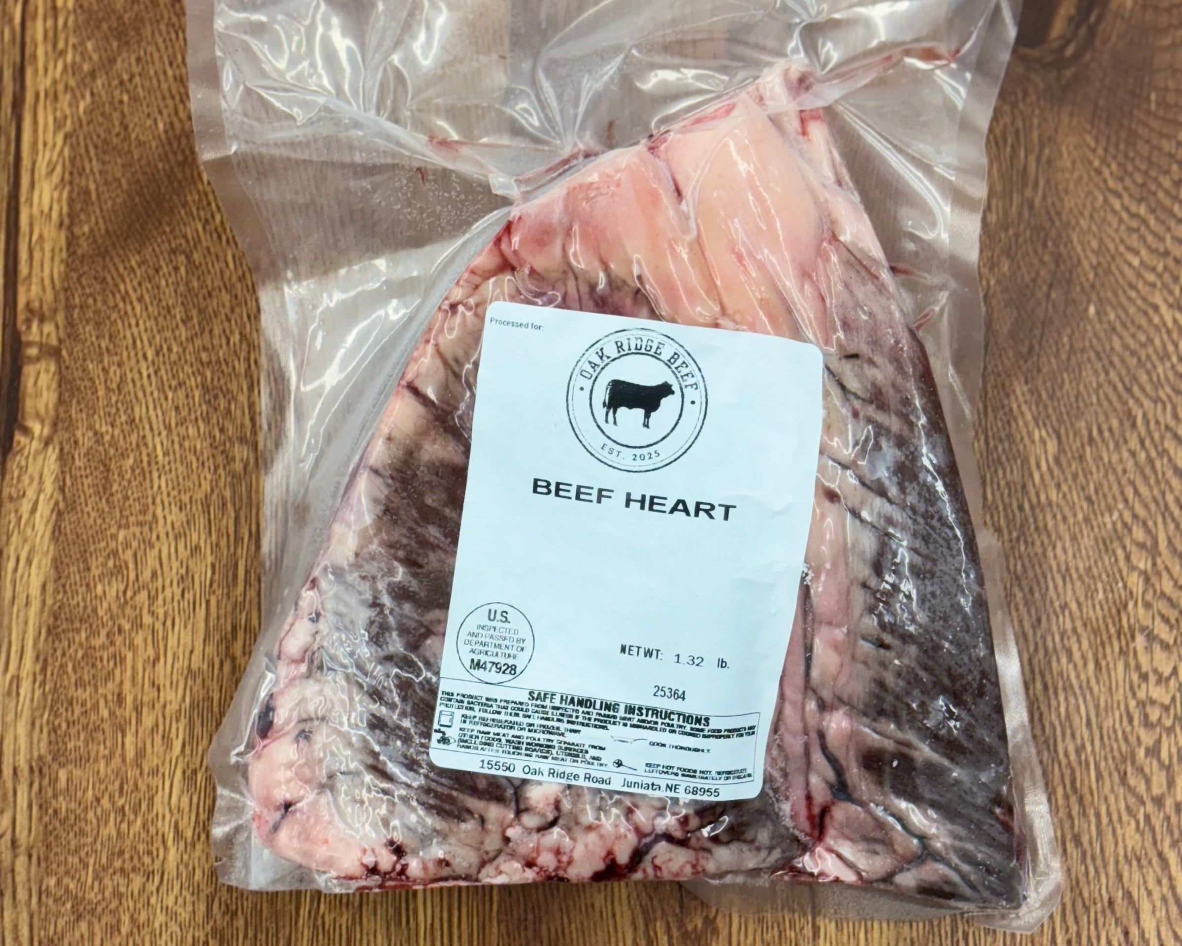 Packaged beef heart on a wooden surface with a label.