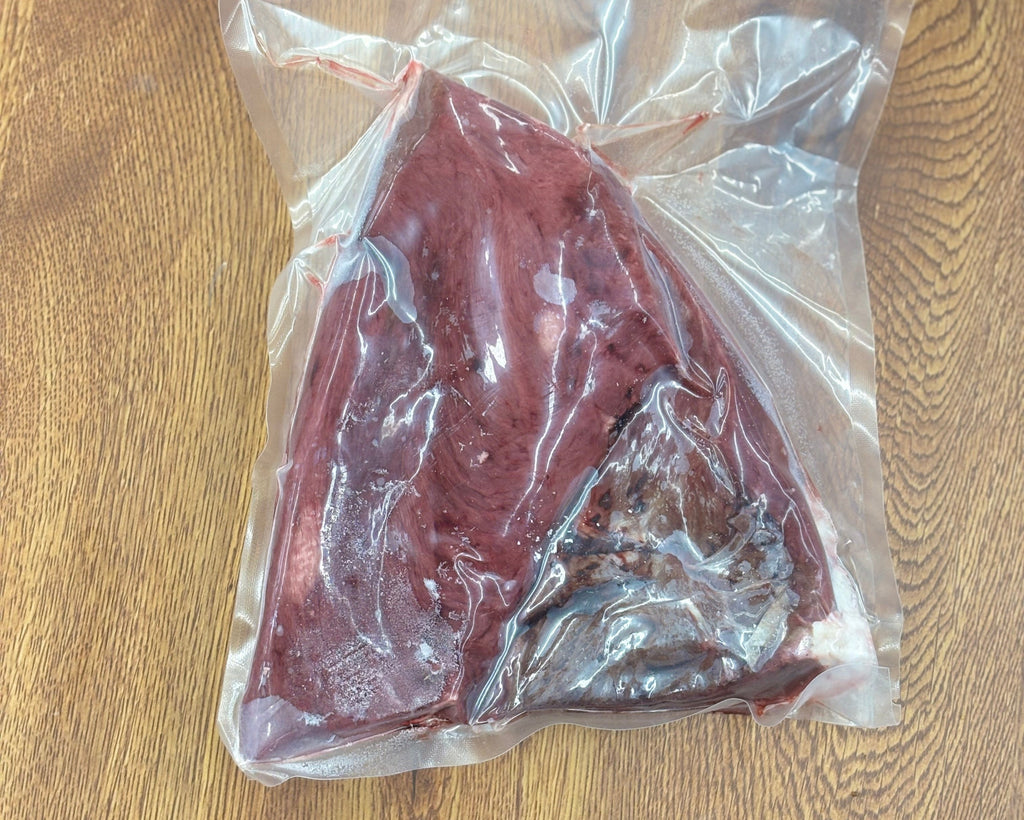 Raw meat in a clear plastic bag on a wooden surface