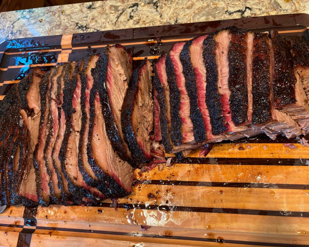 Sliced brisket on a wooden cutting board with a marble countertop background