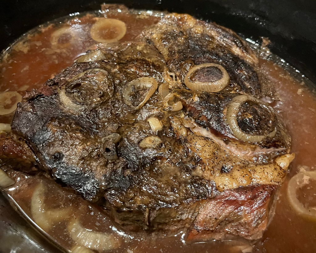 Slow cooker with braised roast and onions in a rich sauce