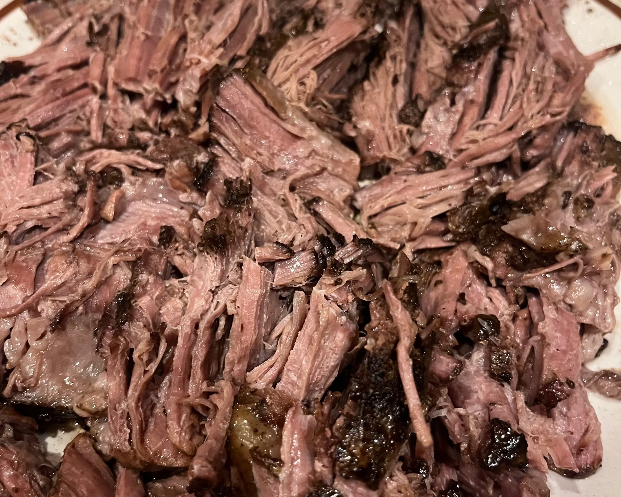 Shredded beef on a white plate with a brown rim