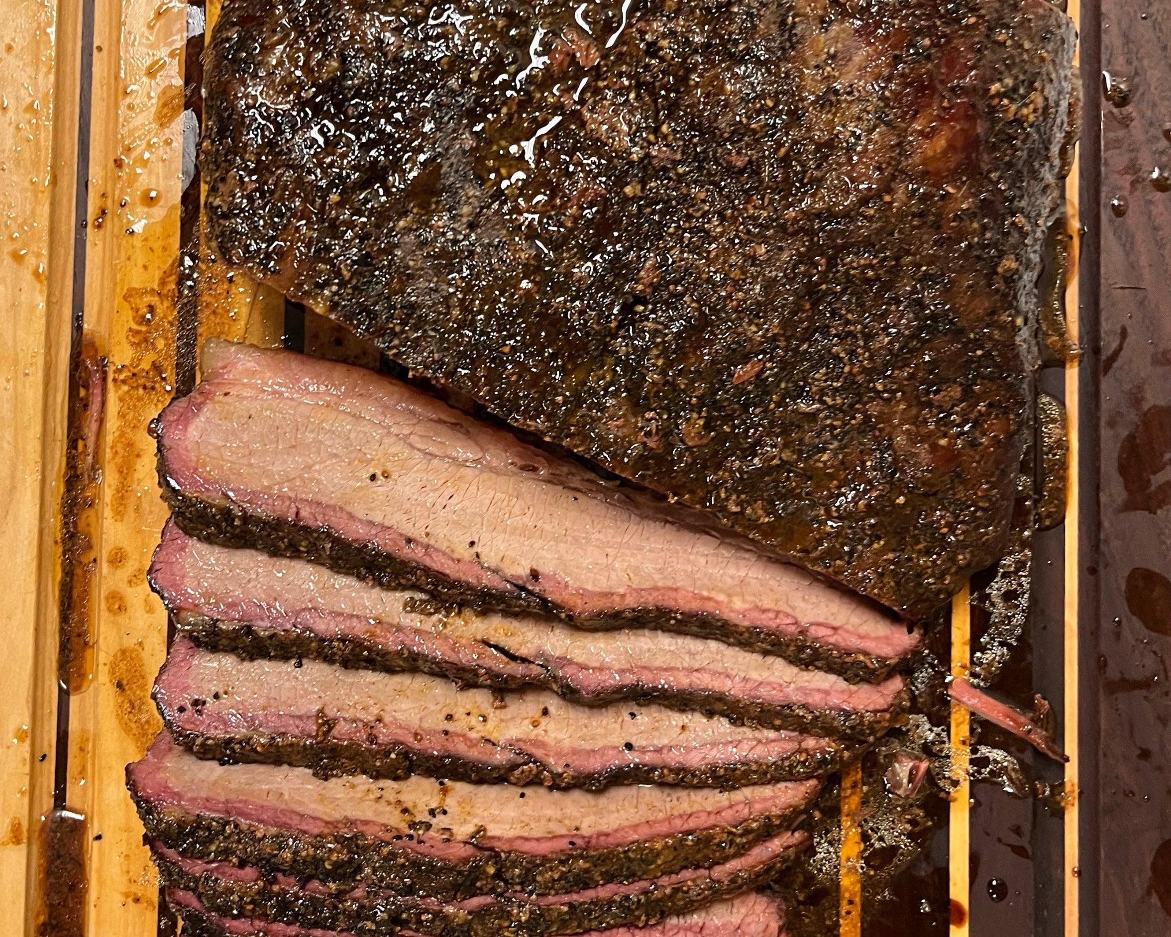 Smoked brisket on a wooden cutting board with a metal knife.